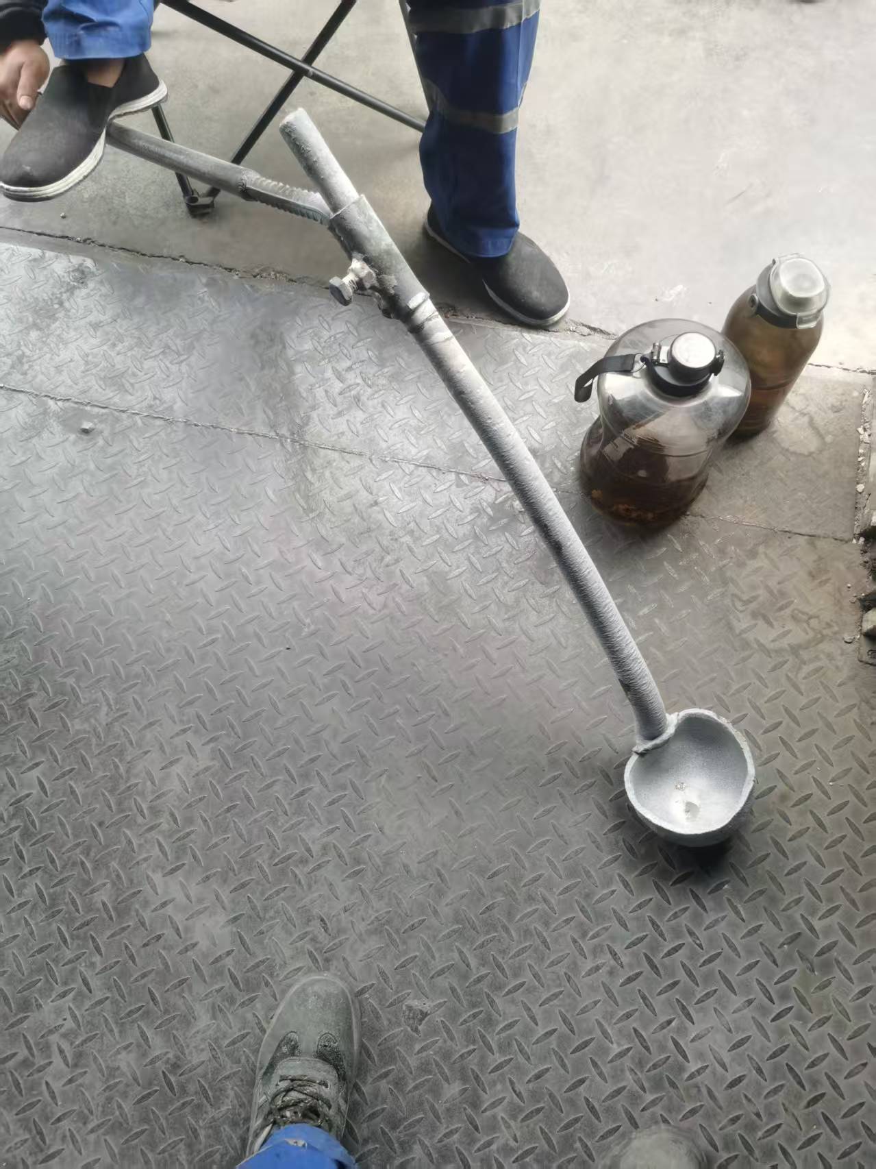 Worn-out sampling ladle in rare earth smelting facility showing severe corrosion and wear - Replacement needed with durable titanium tools